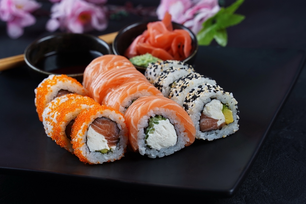 Assorted specialty sushi rolls at a sushi restaurant in Manhattan Beach Brooklyn including salmon rolls topped with roe and sesame-crusted rolls served with soy sauce pickled ginger and wasabi
