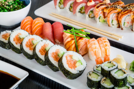 Is sushi healthy — a spread of salmon and tuna nigiri classic maki rolls and specialty rolls served with soy sauce and seaweed salad on white plates